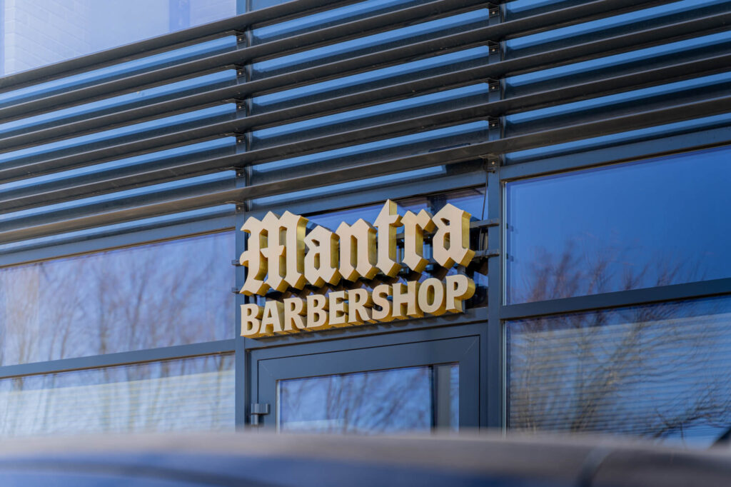 Podświetlany szyld barbershopu ze złotymi bokami liter