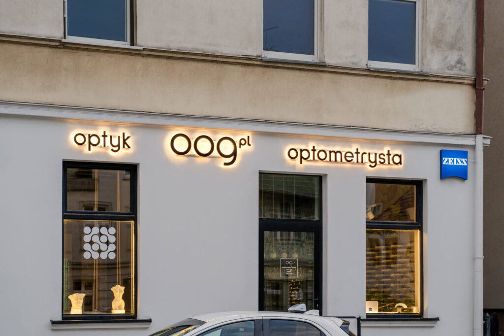 Oznakowanie salonu optycznego z podświetlanymi witrynami o zmroku