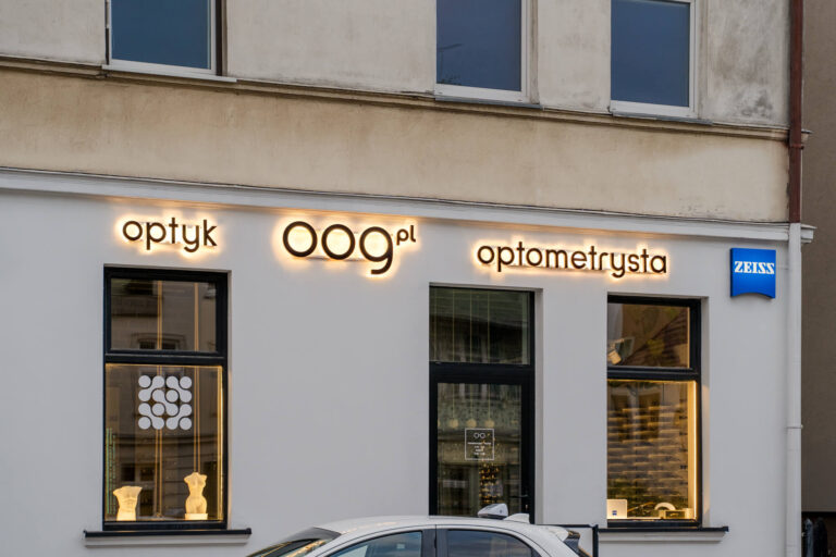 Oznakowanie salonu optycznego z podświetlanymi witrynami o zmroku